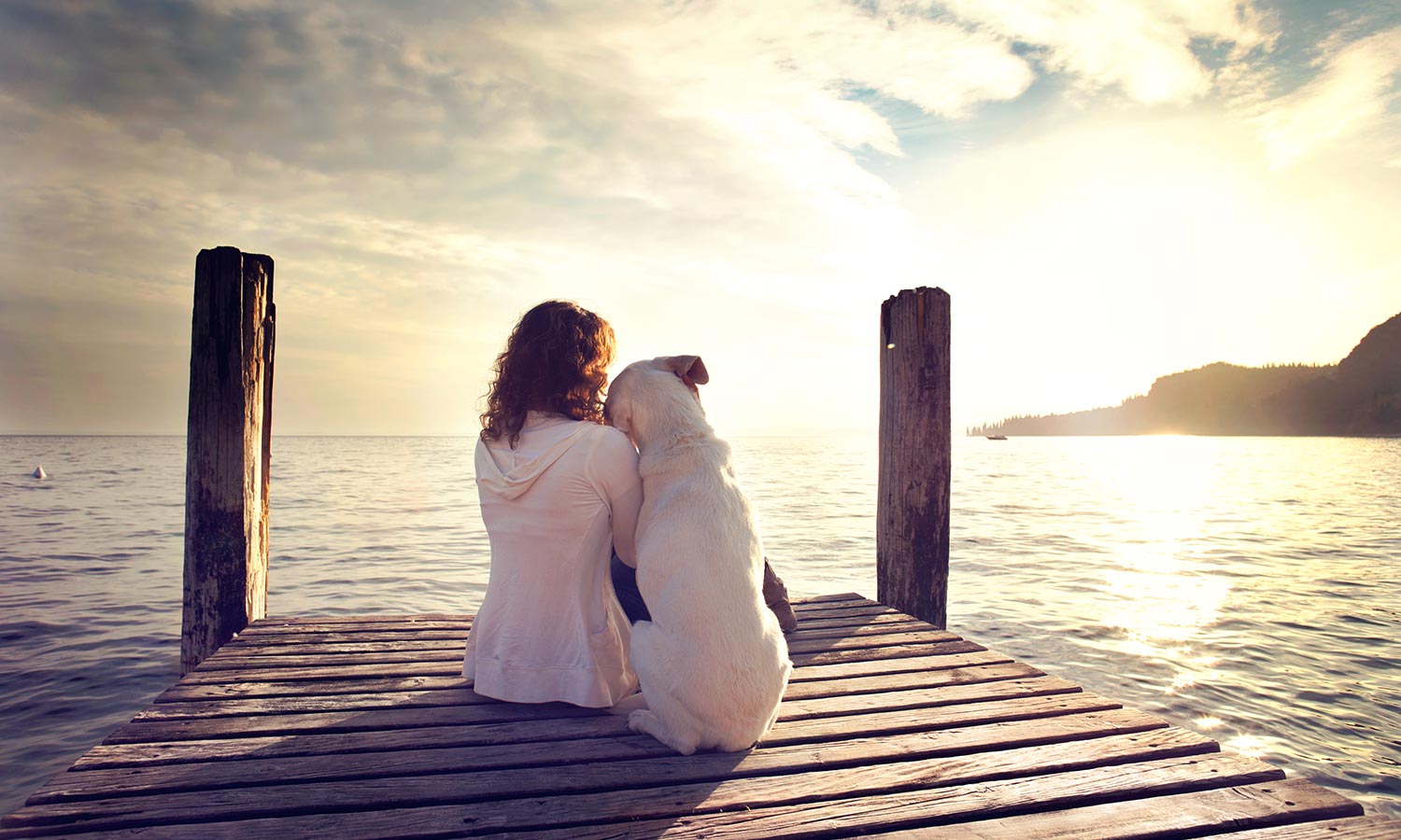 A dog and woman sitting on a dock